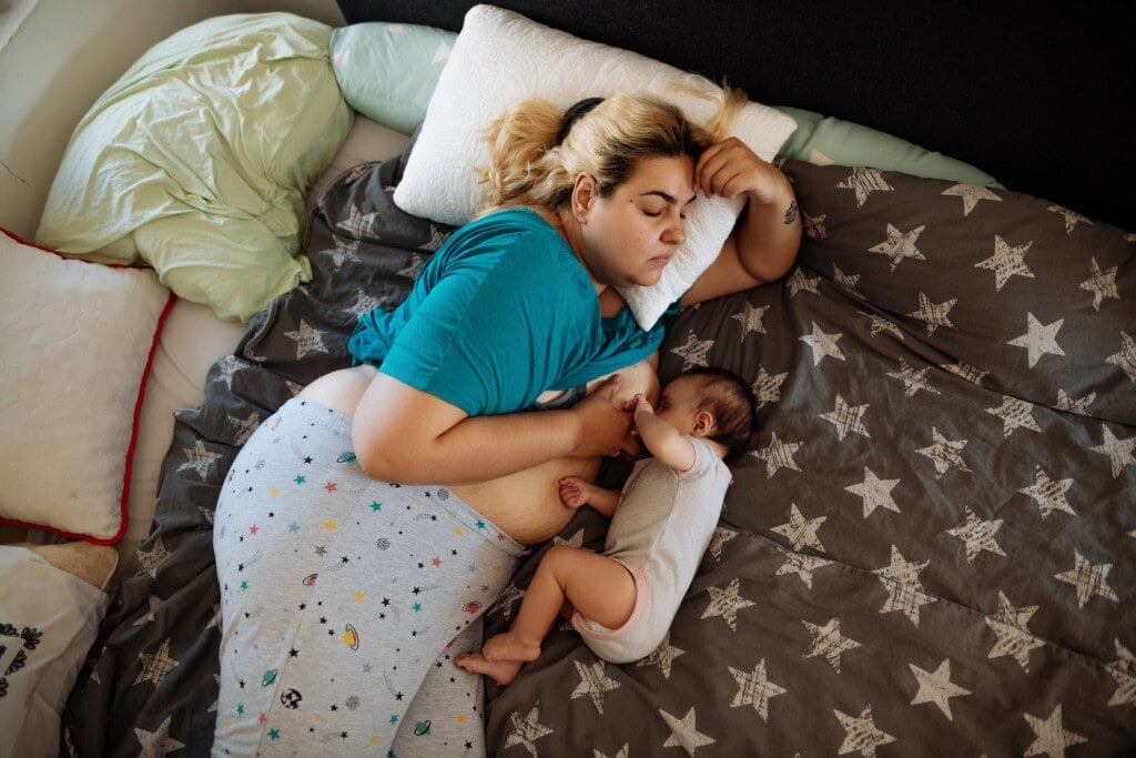 A day in life of real family with five month old baby girl: Millennial mother with visible postpartum body shape breastfeeding baby, putting baby to sleep and feeding baby with help of her husband. Documentary style photos, unedited skin, imperfections or backgrounds. Genuine feel from real family in late 20s or early 30s