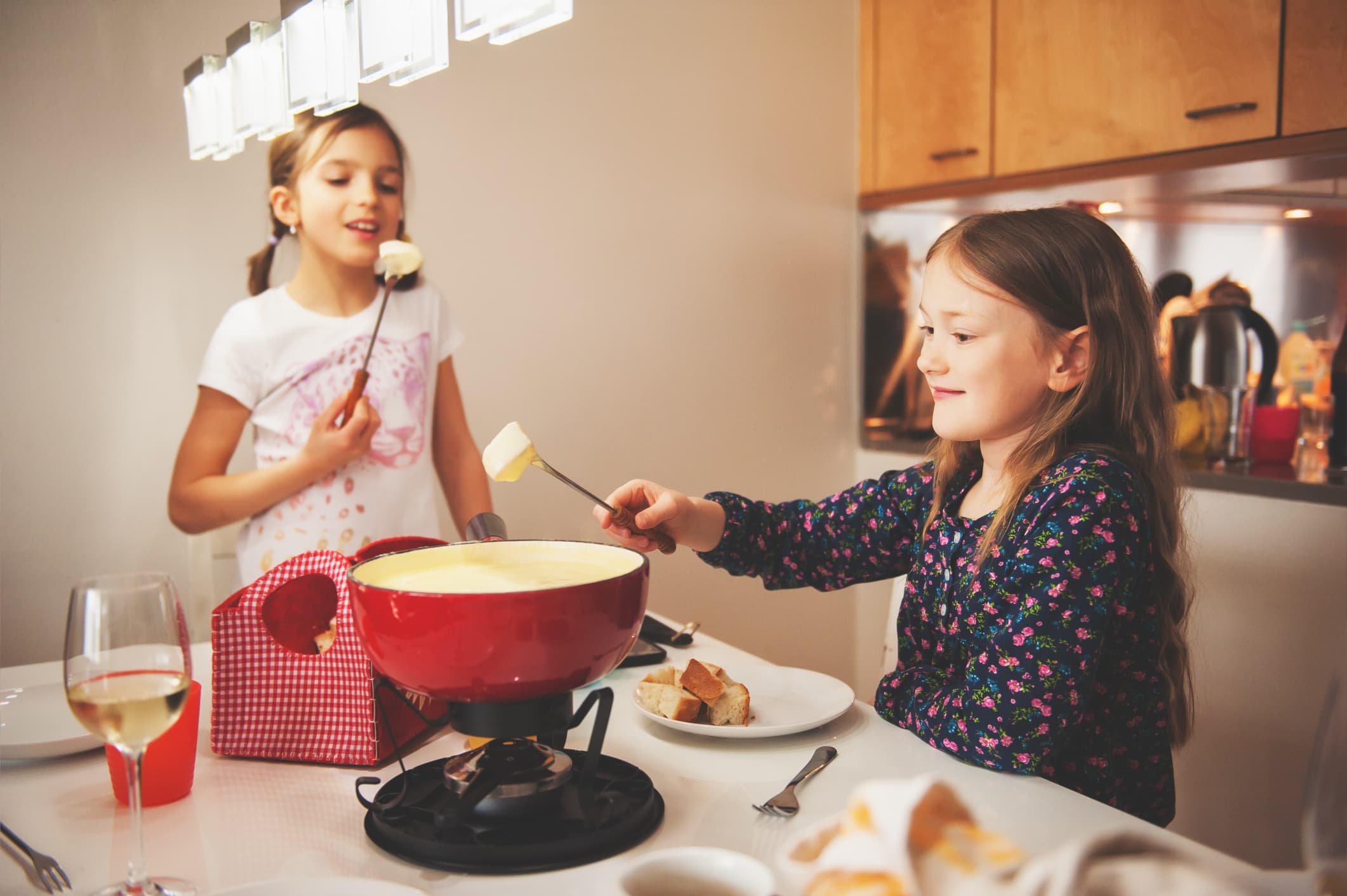 Two kid girls eating swiss fondue for dinner