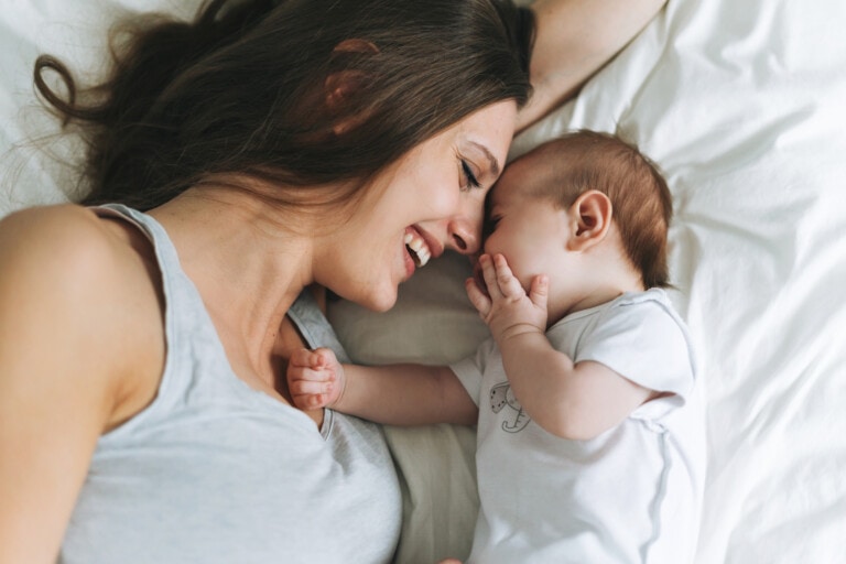 Young mother having fun with cute baby girl on bed, natural tones, love emotion