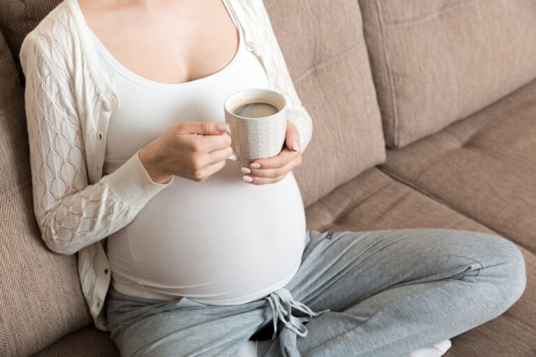 pregnant girl sitting on sofa with coffee Cup in hand coffee.
