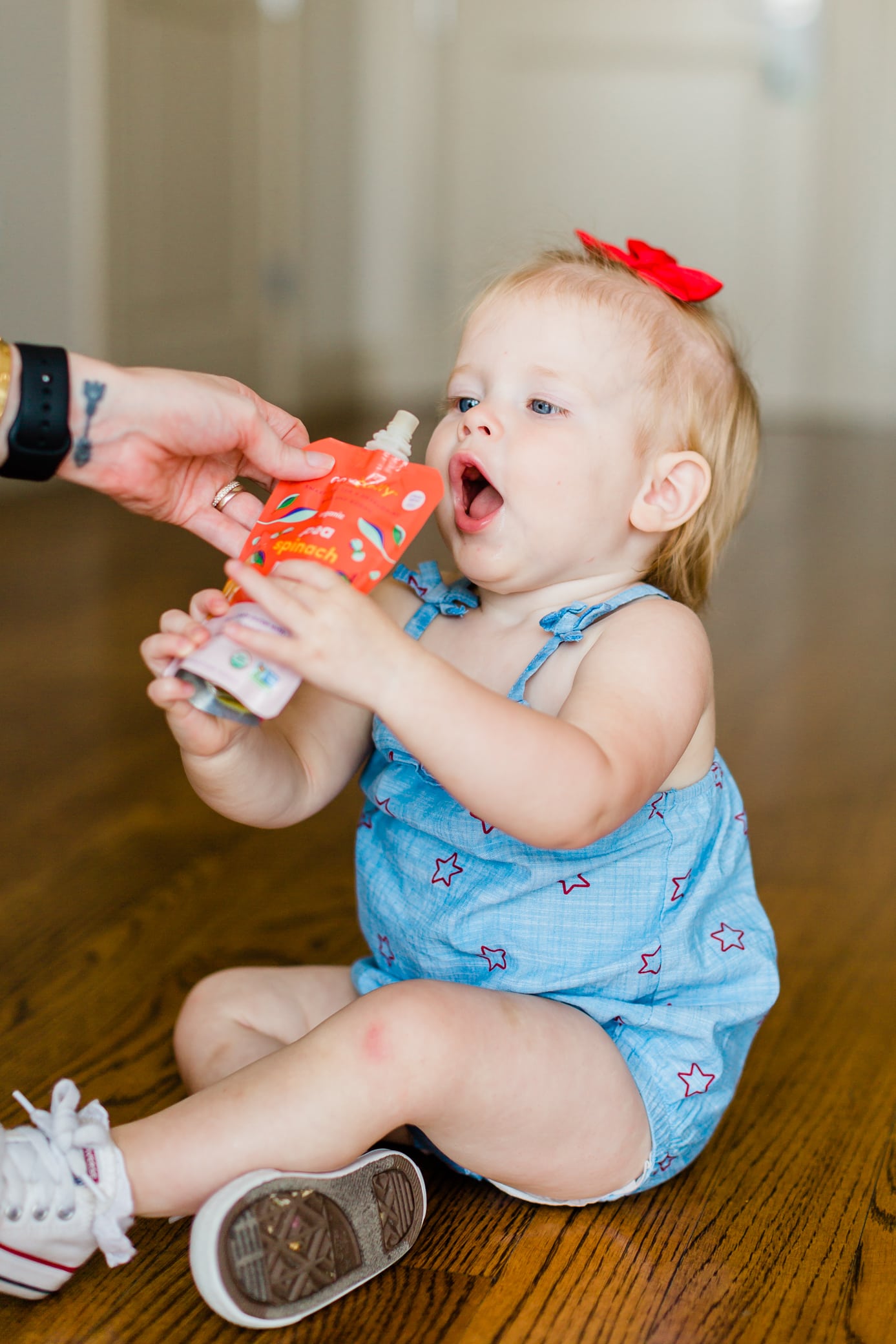 Young toddler girl reaching for a pouch ready to eat.