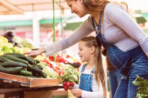 Healthy pregnant mother and daughter choosing organic food for the family