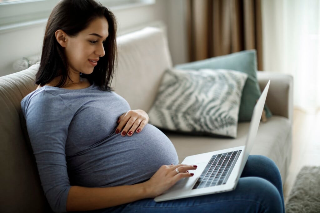 Pregnant woman using laptop at home