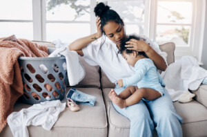 Shot of an attractive young woman sitting on the sofa in her living room and comforting her baby daughter.