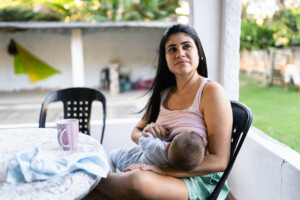 Mom breastfeeding her baby in her backyard.