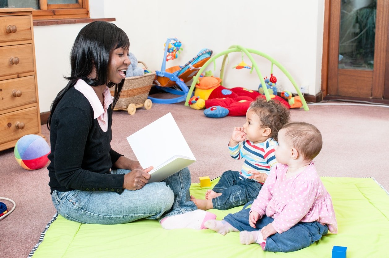 An African American woman reads a story to a group of babies