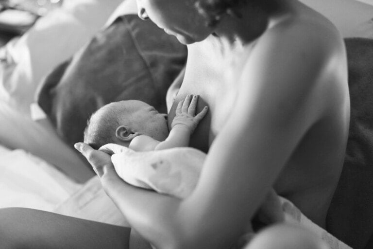 Mother breastfeeding newborn for the first time after home birth.