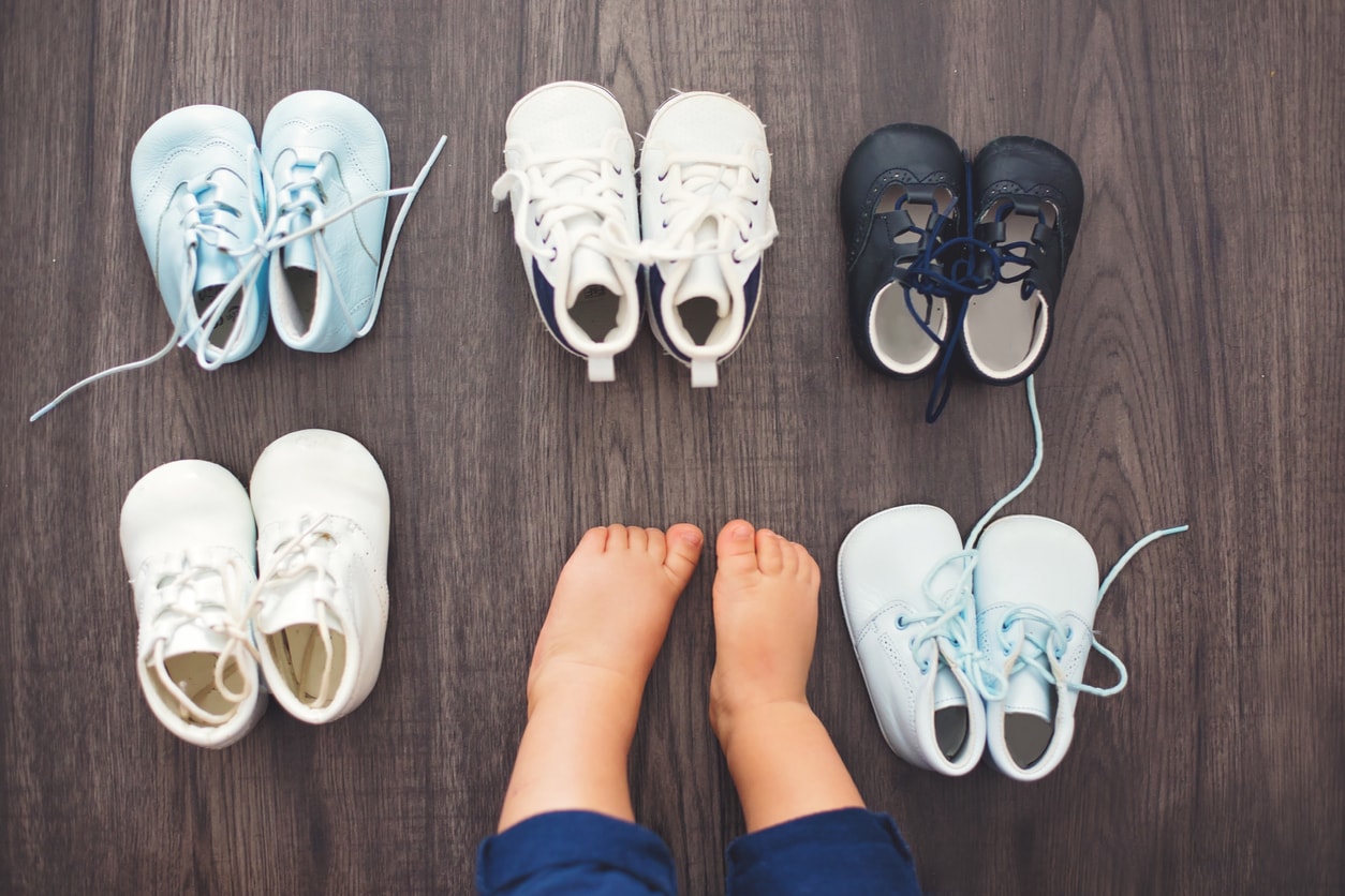 Children shoes and baby feet on a wood background