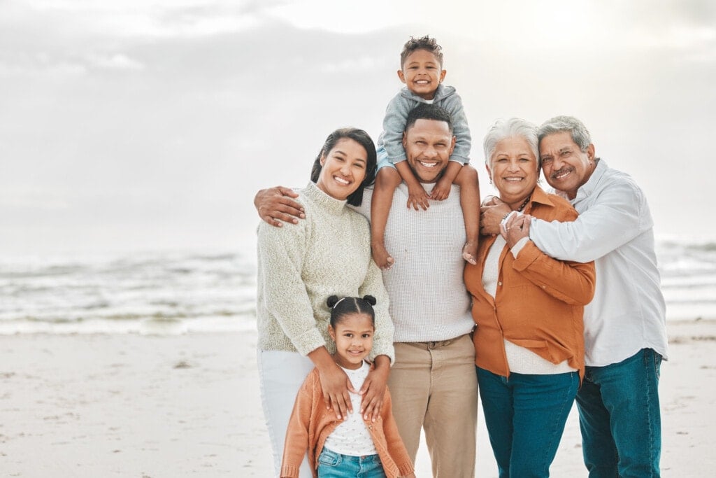 A family standing on the beach taking a family photo.