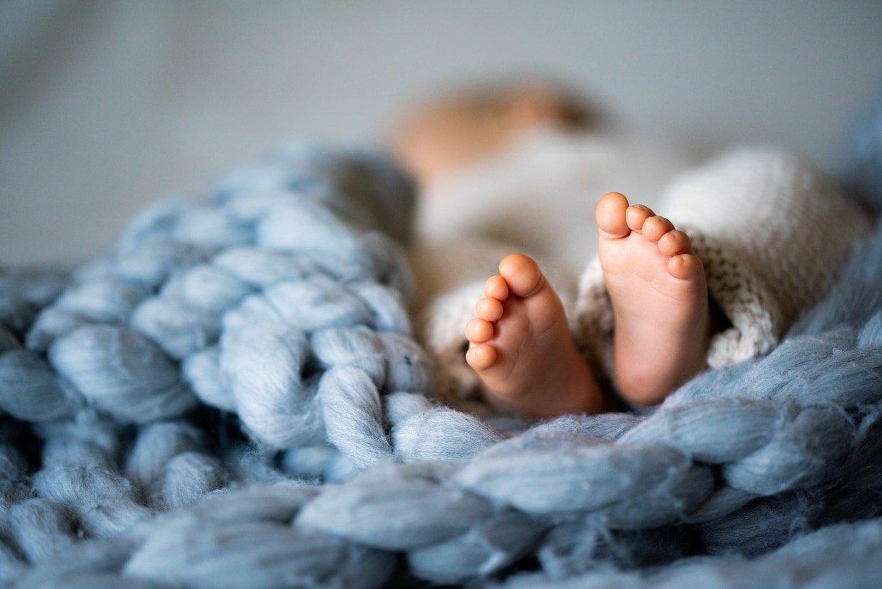 Feet of newborn baby on warm woven blue blanket