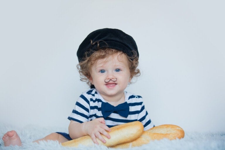 Little baby with mustache, beret and baguette on white background.