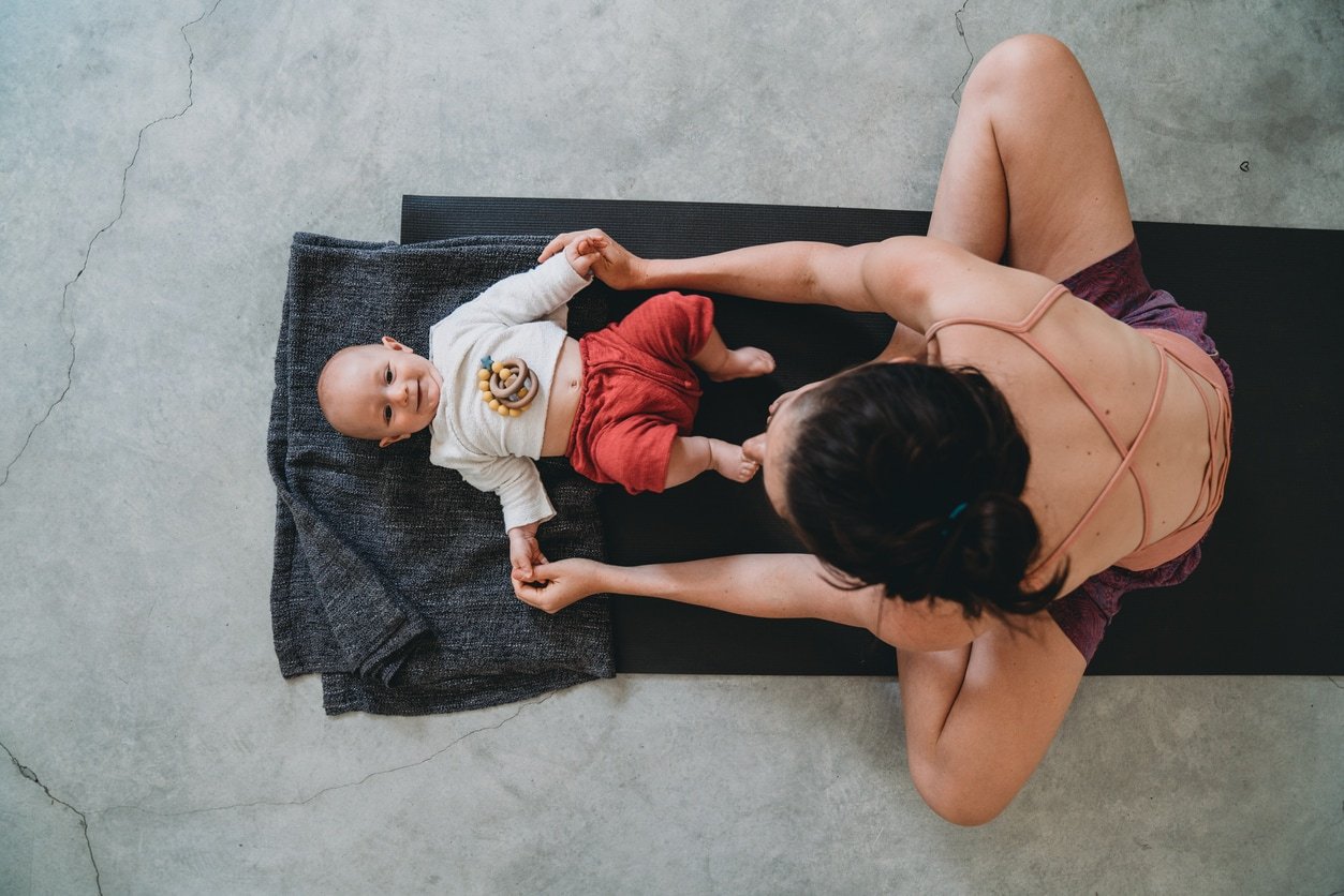 Mother having fun with her little kid during a yoga class. They are in a yoga gym.