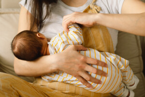Newborn baby boy sucking milk from mothers breast. Portrait of mom and breastfeeding baby. Concept of healthy and natural baby breastfeeding nutrition.
