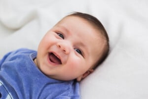 close up of smiling baby lying in his crib