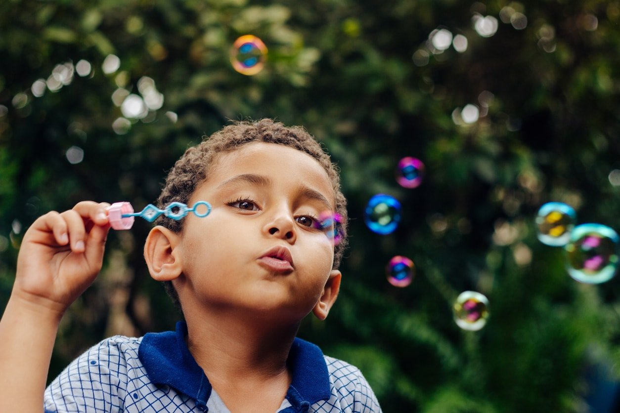 Boy playing soap bubble. Blowing bubbles outside.