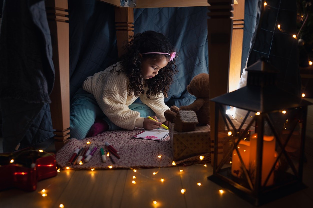 Girl writing a Christmas wish list under the improvised tent