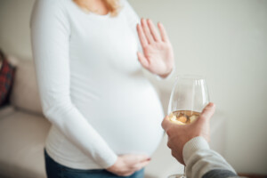 Pregnant woman refusing a drink of wine.