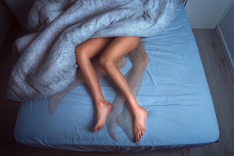 Woman sleeping in the bed and suffering from RLS or restless legs syndrome.