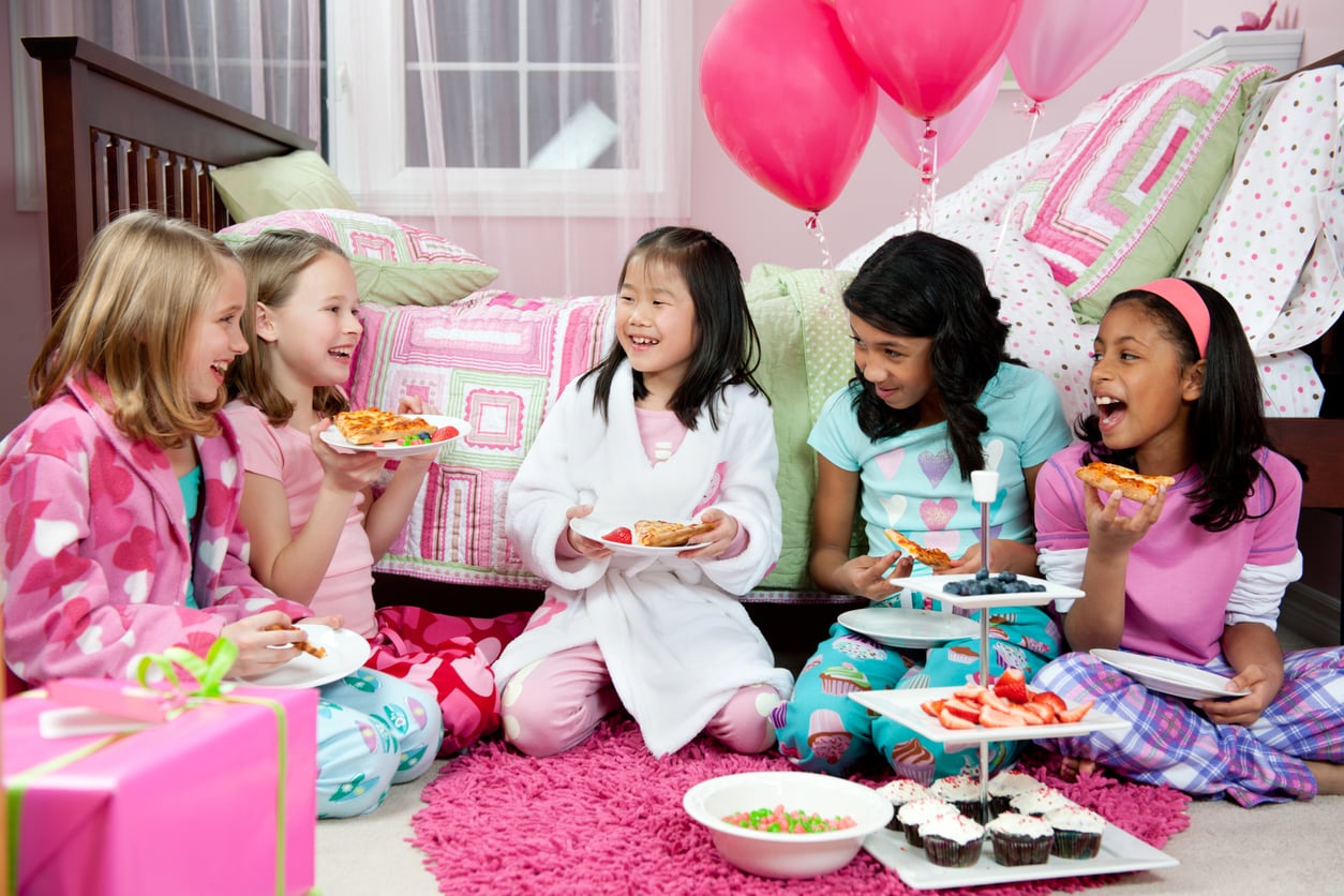 A diverse group of girls having a snack at a sleepover.
