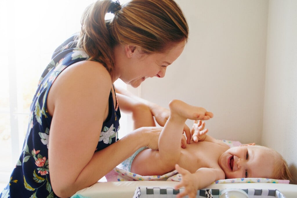 Shot of a young woman changing her adorable baby girl’s diaper on a table at home