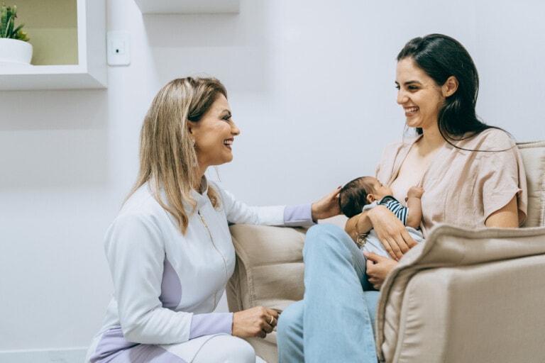 Nurse, doula, lactation consultant accompanying mother and baby while mother breastfeeds.
