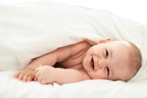 A happy baby lying on white sheets