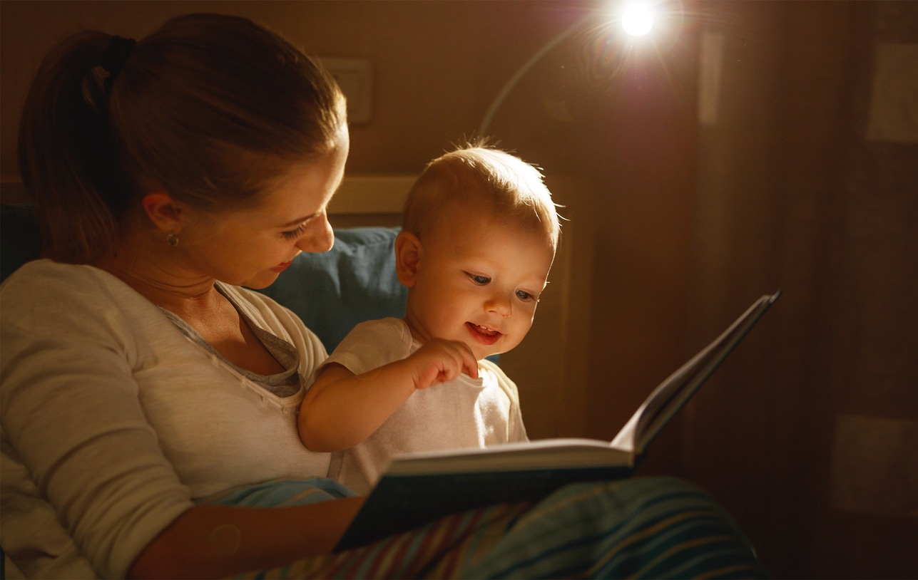 mother reads to baby the book before going to sleep in bed