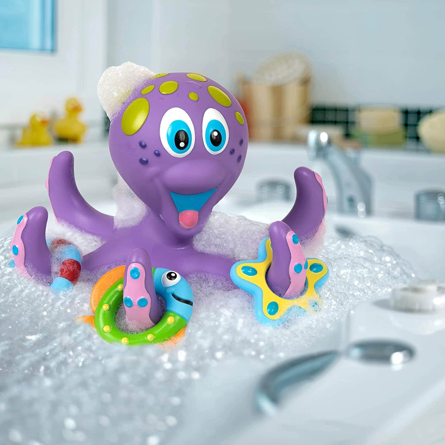 Purple toy octopus in bath water with green polka dots and toy rings on its tentacles. 