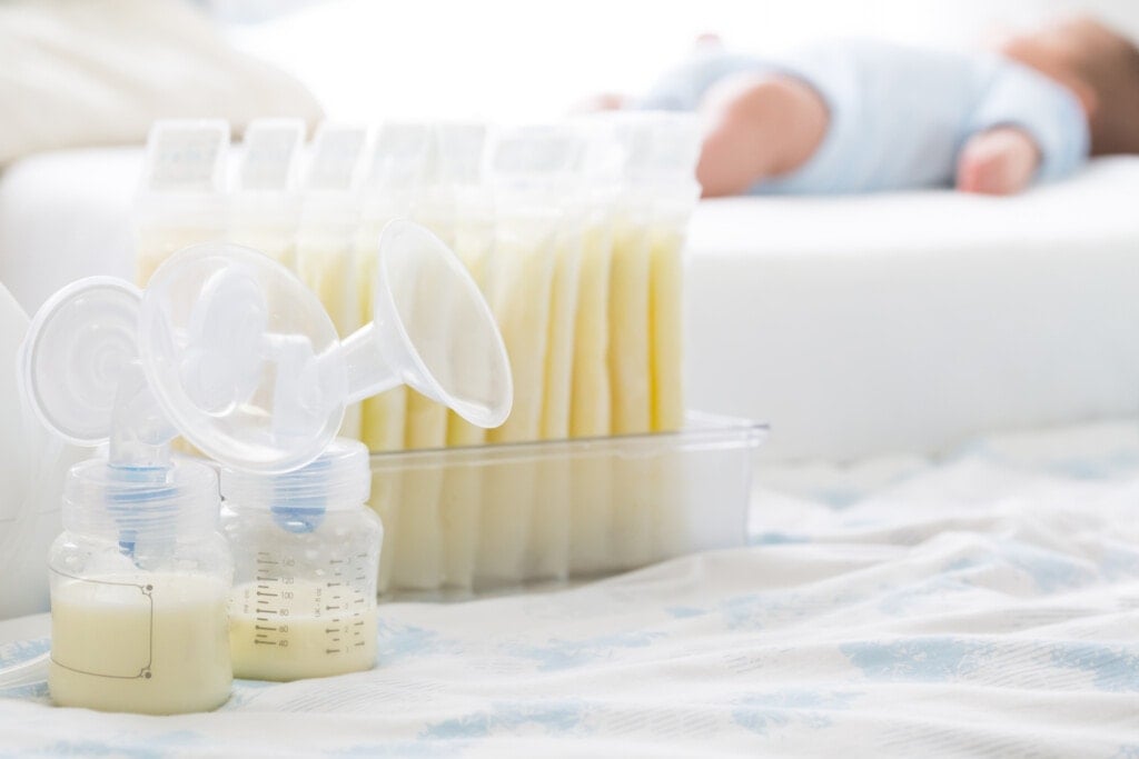 Breast milk frozen in storage bag and baby lying in background