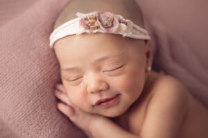 Cute 14 days-old baby girl sleeping comfortably with a sweet headband
