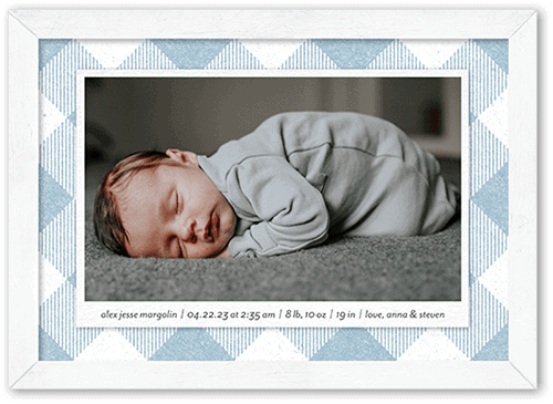 Framed photo with blue and white tartan print bordering the image of a baby and text announcing the birth. 