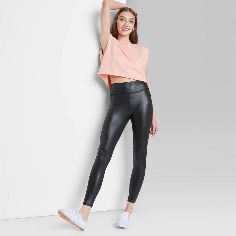 Woman in black faux leather leggings, pink cropped tee, and white sneakers 