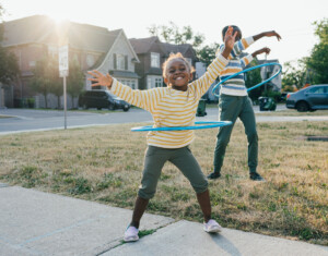 Joy and happiness being outdoor with friends and siblings. Two kids are outside playing with their hula hoops.