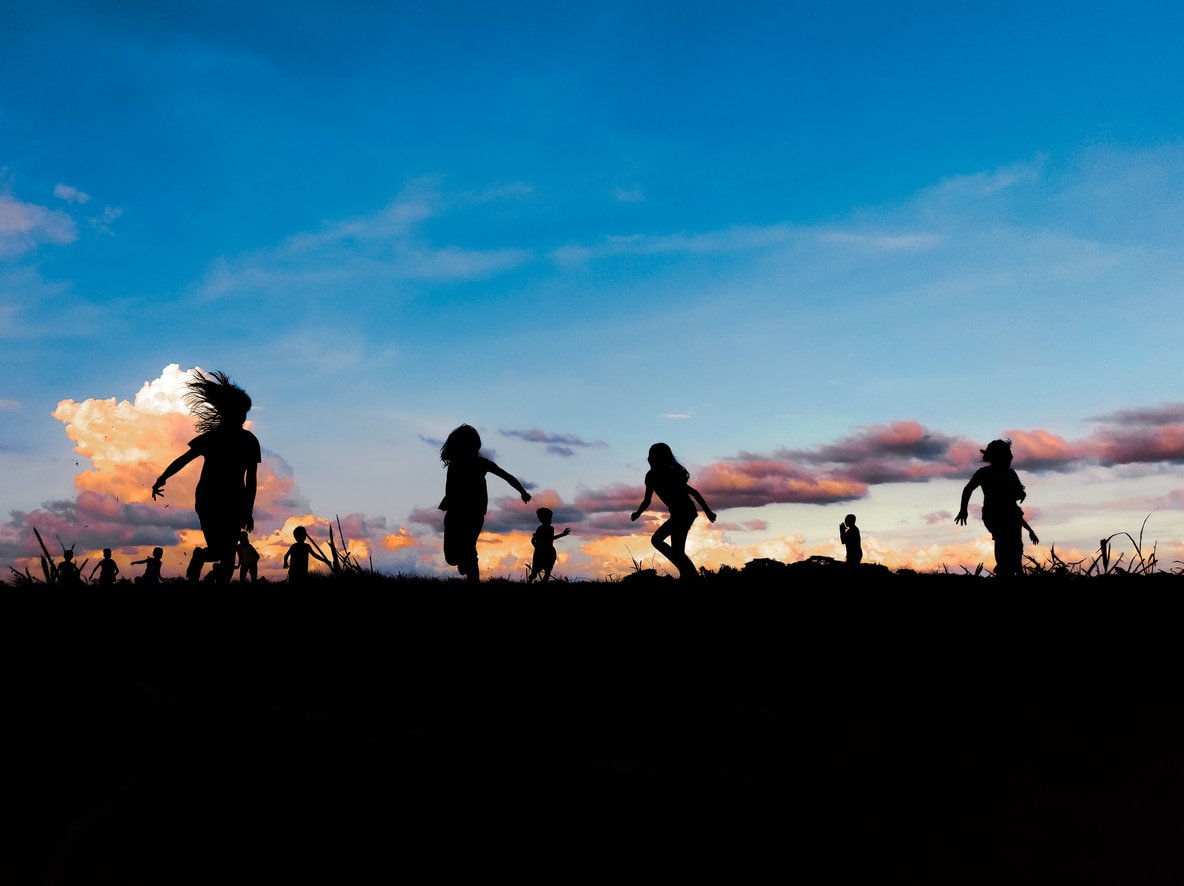 Children playing on vacant lot in during sunset.