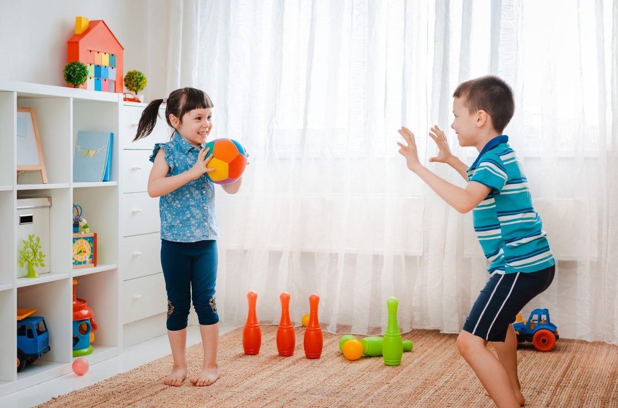native children boy and a girl play in a children's game room, throwing ball.