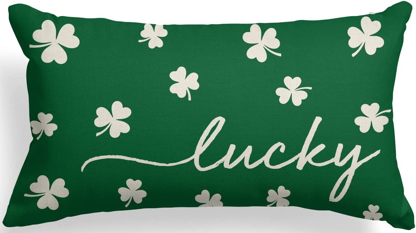 Green throw pillow with white shamrocks on it and it says lucky 