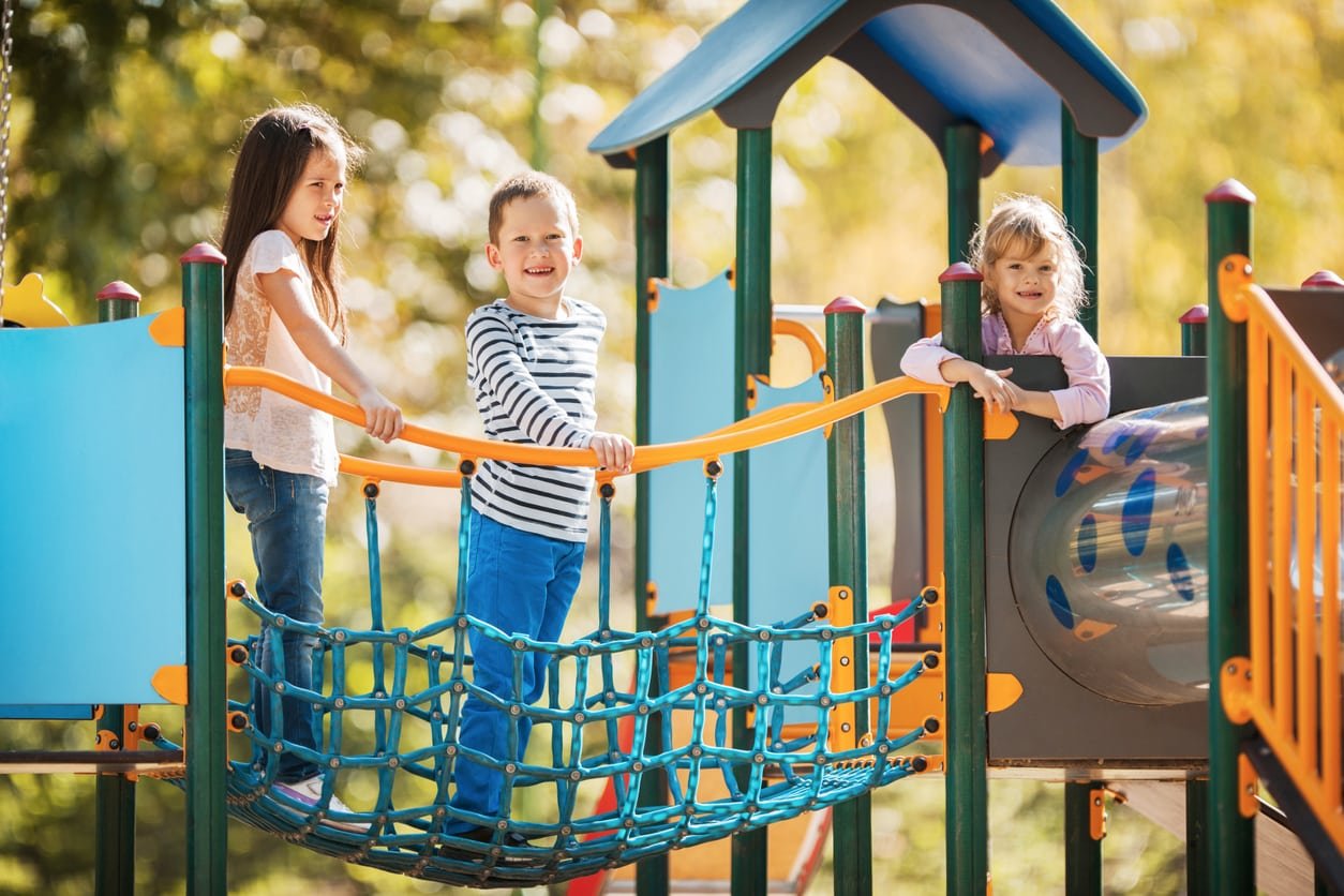 Three smiling children enjoying at the playground.
