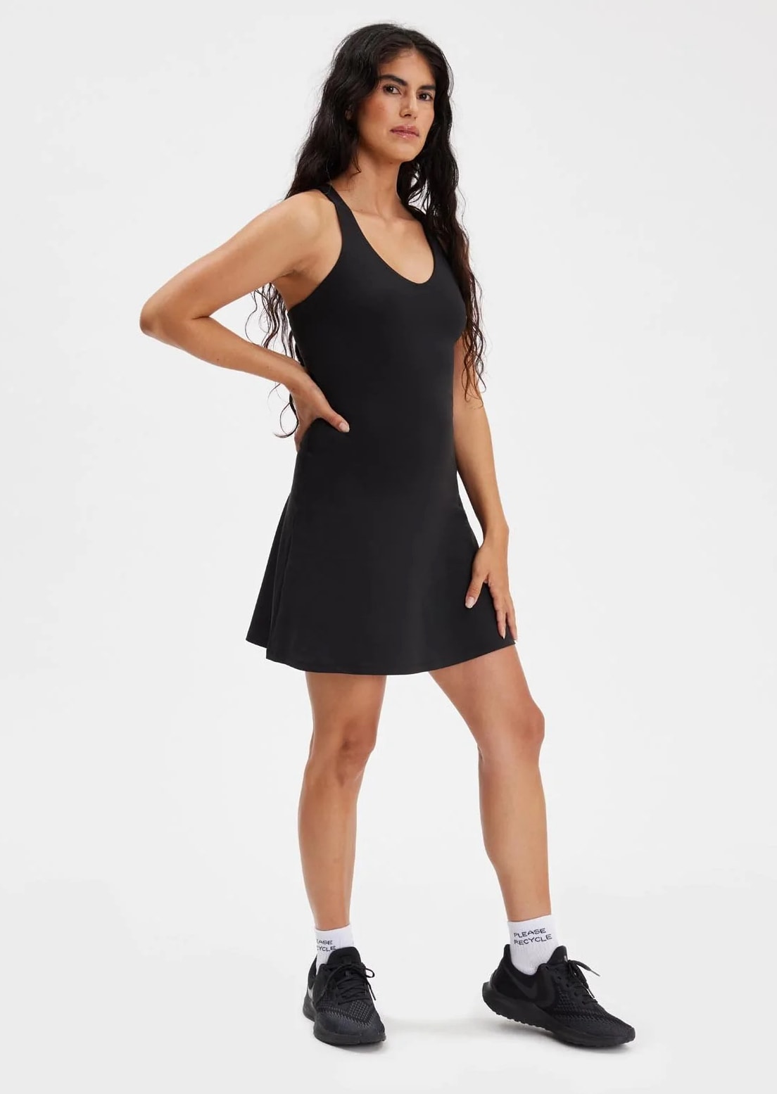 Woman in black sleeveless v-neck athletic dress and black sneakers 