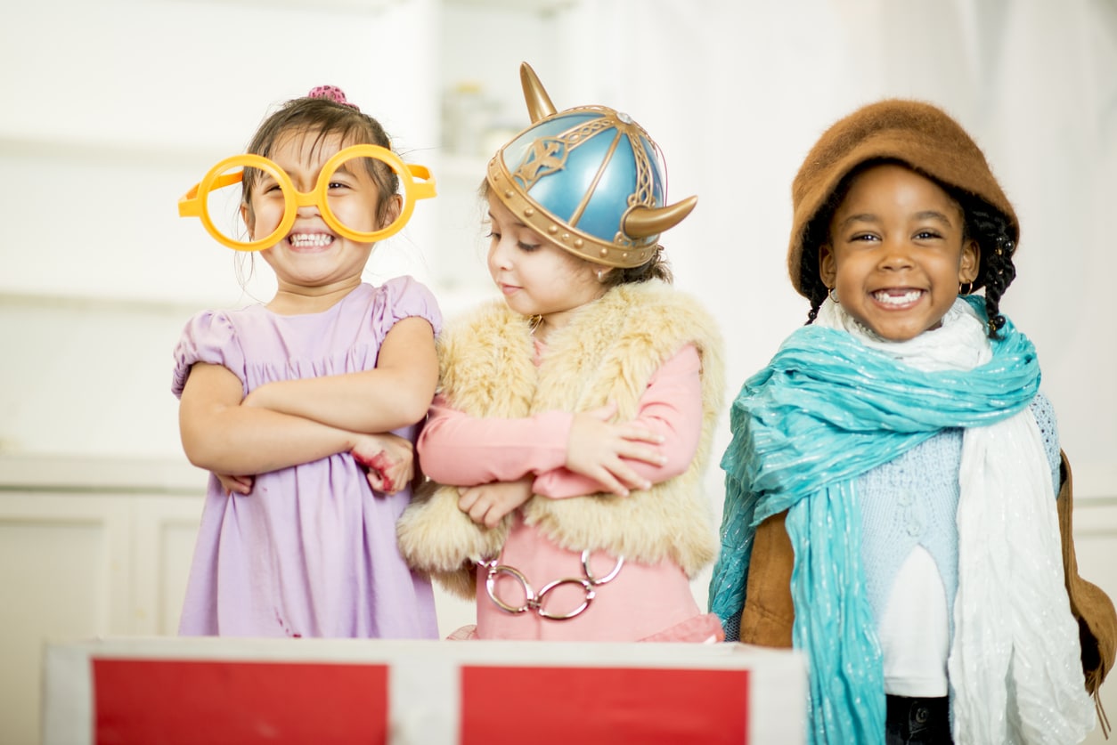 Little girls dressed in theatrical costume laughing and smiling together.