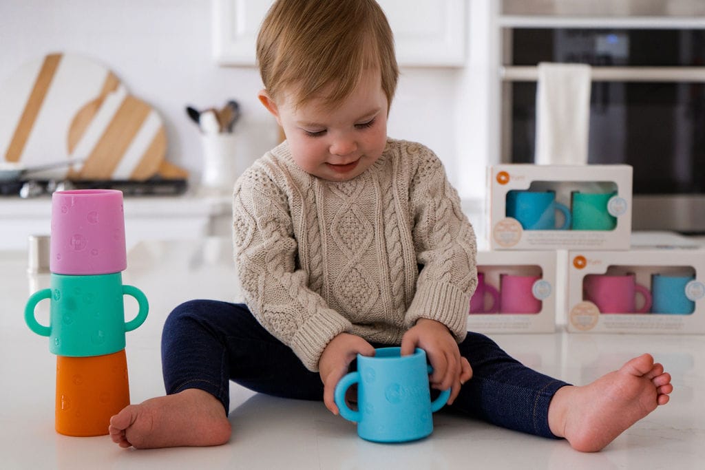 Baby sitting on a kitchen counter with PopYum silicone cups