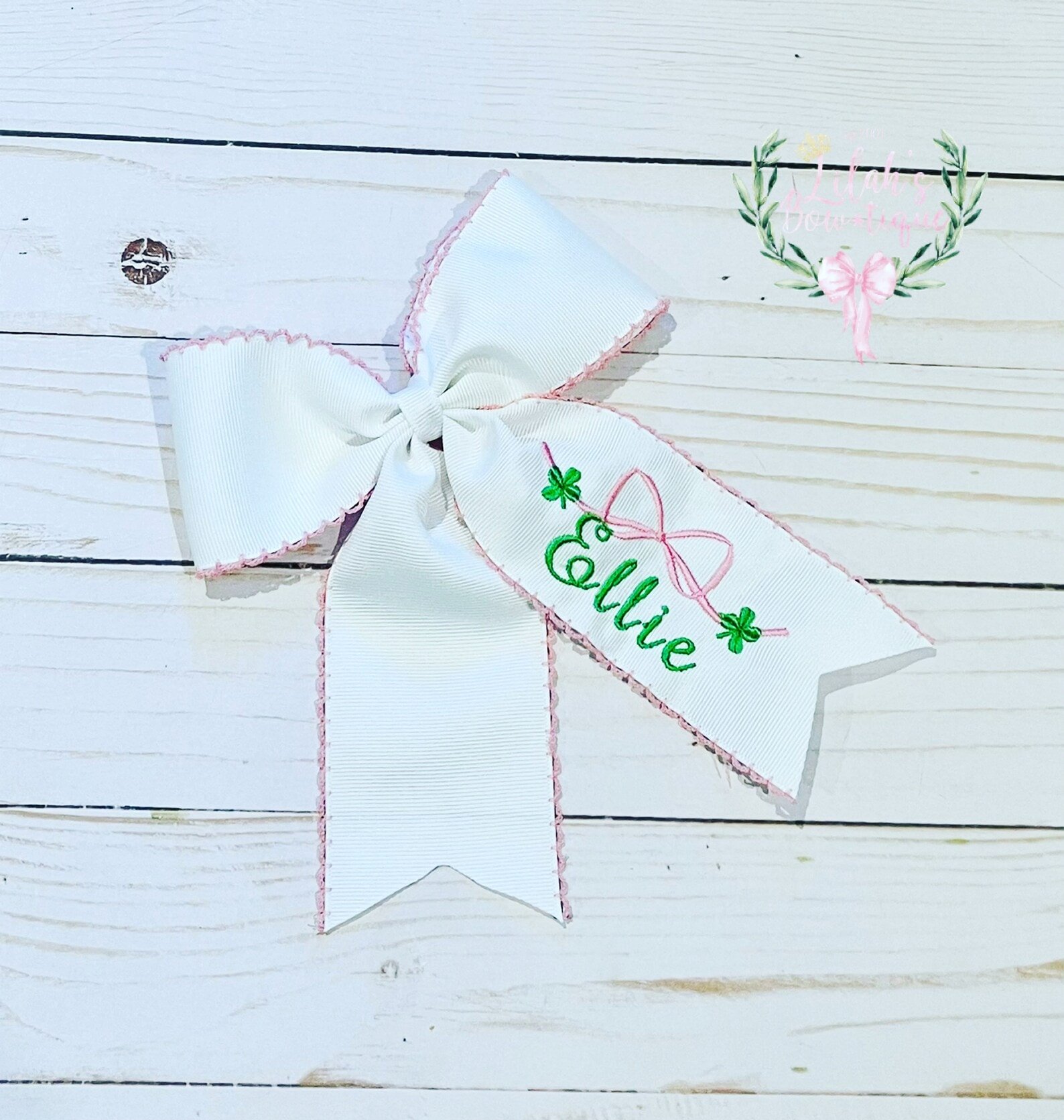 White embroidered hair bow with green shamrocks on it 