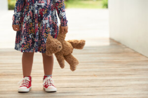Cropped image of girl standing outdoors with teddy bear