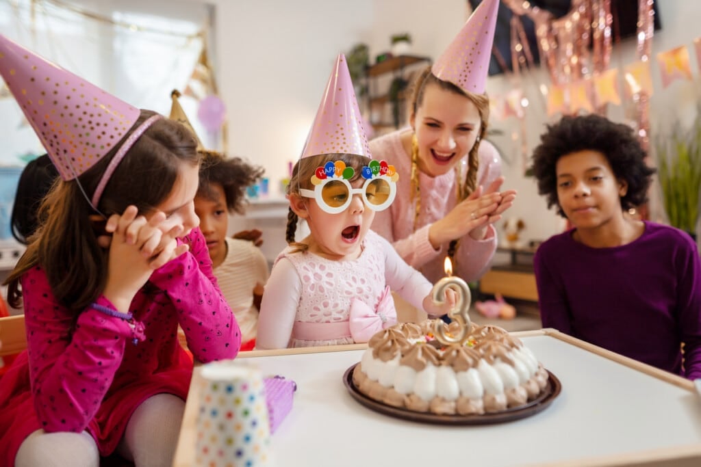 Little girl blowing her birthday candle wearing birthday glasses