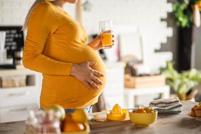 Midsection of future mother drinking a freshly-squeezed orange juice to keep her immune system healthy and strong during her pregnancy.