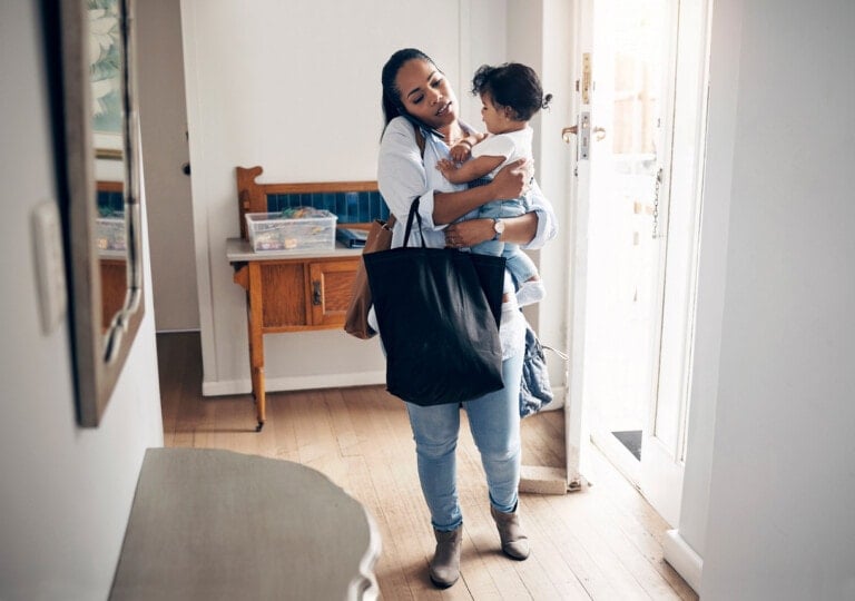 Shot of a young woman looking annoyed while talking on a cellphone and carrying her daughter at home with a bag