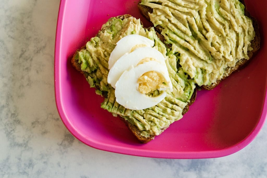 Avocado toast with sliced boiled egg on top. They are on a hot pink kid's plate