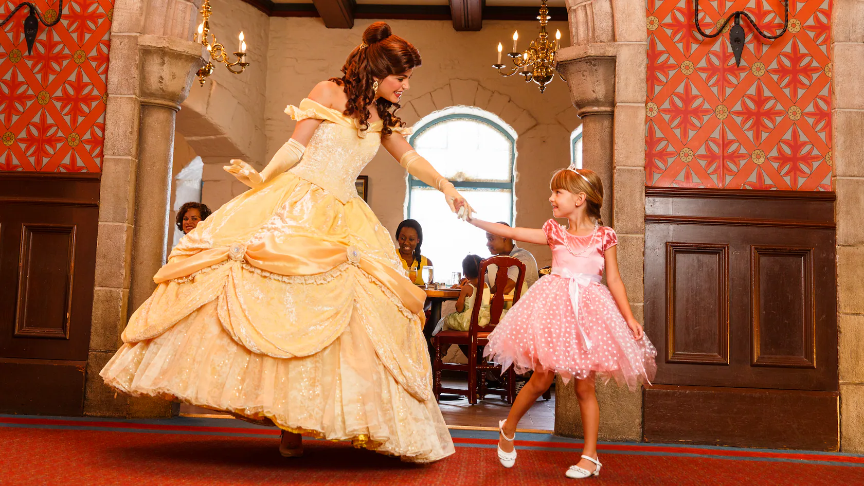 Belle from Beauty and the Beast and a little girl dressed as a princess holding hands in Akershus Royal Banquet Hall