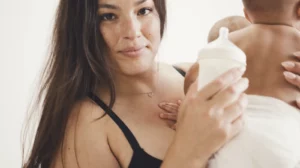 Ashley Graham holding her baby and a bottle of formula milk