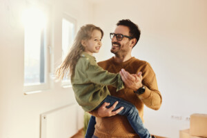 Happy single father having fun while dancing with his small daughter after moving into a new apartment.