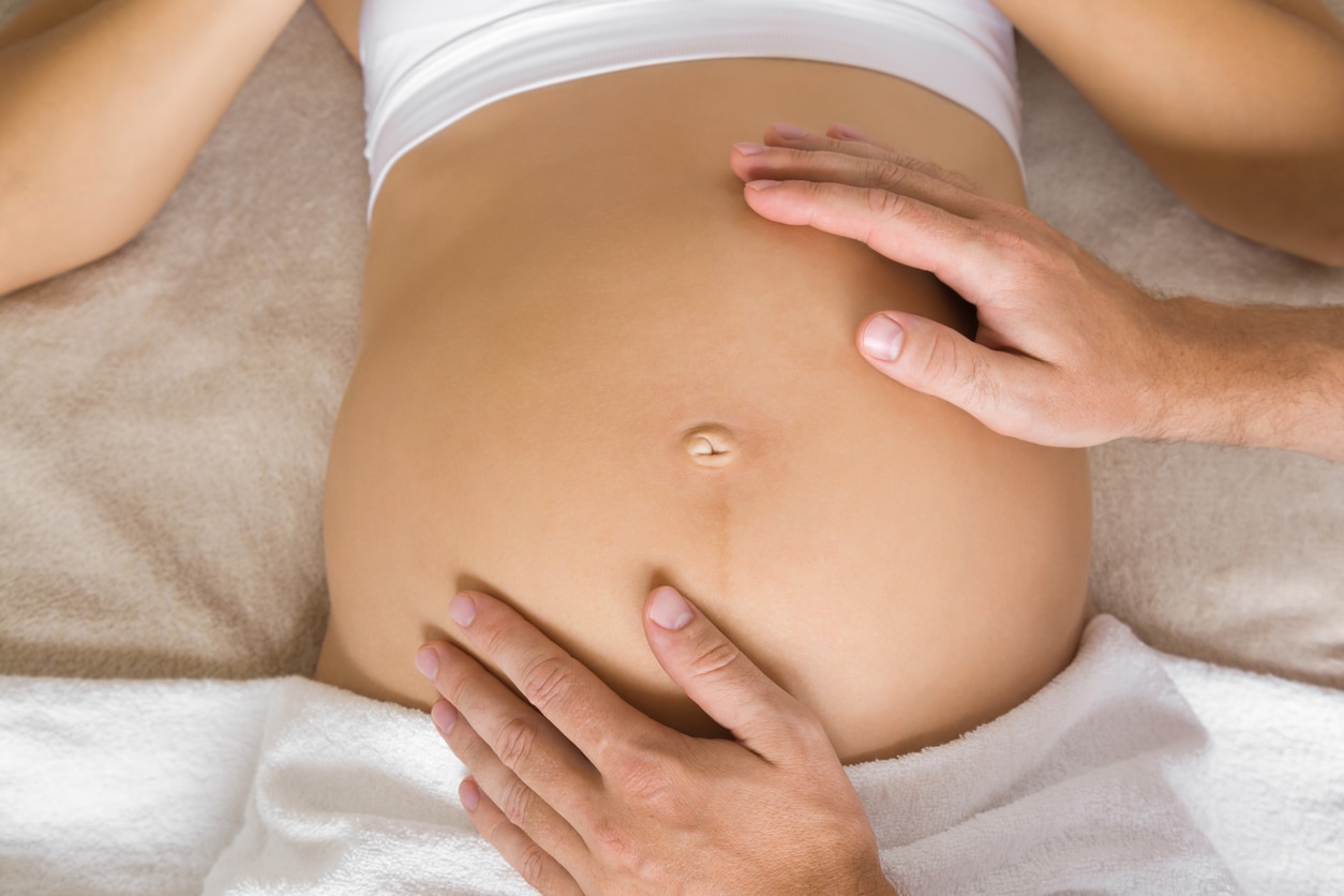 Man hands touching pregnant woman belly. Lying down on bed. Breech baby. Problems in pregnancy time.